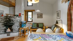 Una sala de estar acogedora con chimenea de piedra, una mesa de comedor de madera y un espacio de estar cómodo.