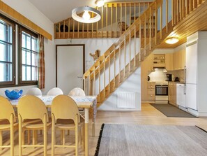 Een moderne keuken met houten kastjes, een inbouwoven en een eethoek met een tafel en stoelen.