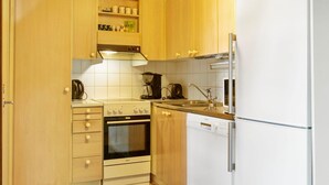 Una cocina compacta con armarios de madera, estufa, fregadero y lavavajillas.