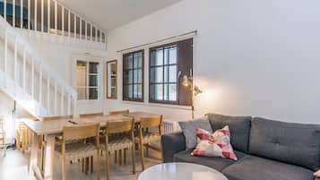 Un salon moderne avec un escalier, un coin repas et un canapé gris agrémenté de coussins.