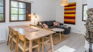 A modern living room with a dining table, sofa, and a hanging light fixture. - Saarihely a1 by Interhome (Inari)