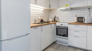 A modern kitchen with white cabinets, a wooden countertop, a stove, an oven, a microwave, and a sink. - Saarihely a1 by Interhome (Inari)