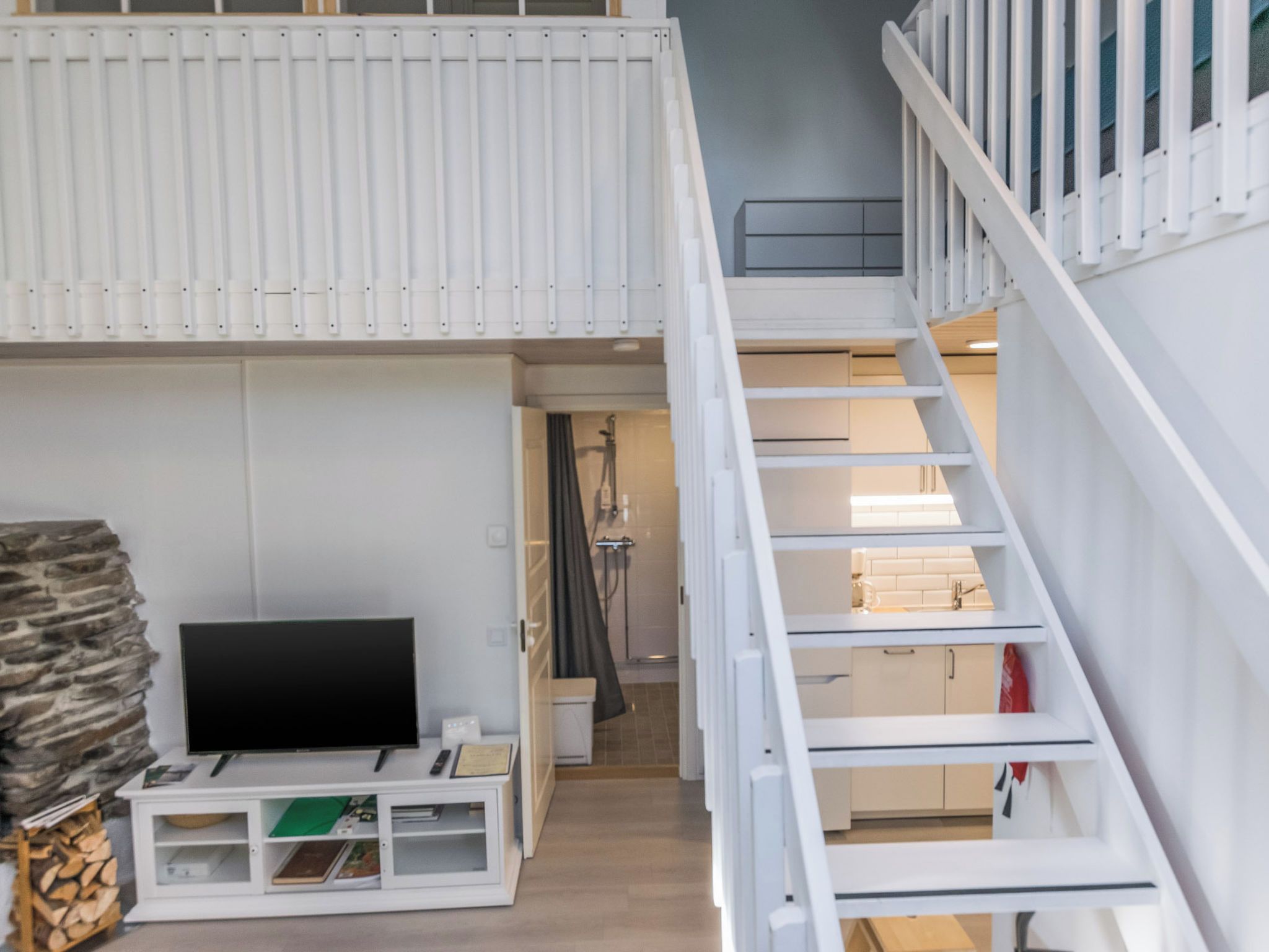 A modern interior with a TV, storage unit, and a staircase leading to an upper level.