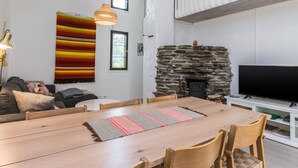 A modern living room with a stone fireplace, a dining table, and a sofa. - Saarihely a1 by Interhome (Inari)