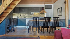 Une cuisine moderne avec un coin repas, un escalier en bois et un luminaire suspendu.