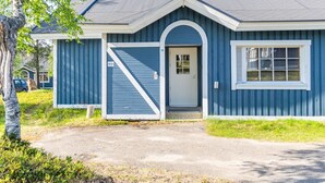 Une maison de plain-pied à l’extérieur bleu, avec une porte d’entrée surmontée d’un arc blanc et une porte de garage.