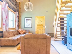 A cozy living room with a sofa, a wooden door, a framed picture, and a ladder.