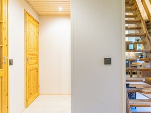 A hallway with wooden doors and a staircase leading to an upper level.