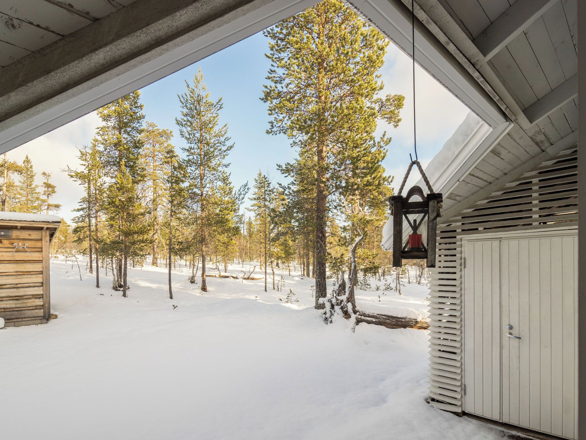 Ett snöigt landskap med en trästuga och en vit byggnad med en dörr.