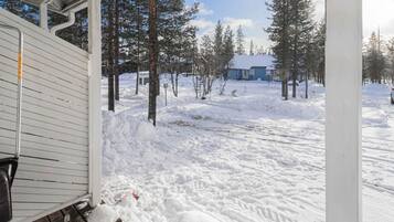 A snow-covered outdoor area with a wooden bench and a building in the background.