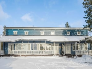 Un bâtiment à deux étages, doté d’un porche abrité et d’un toit recouvert de neige.