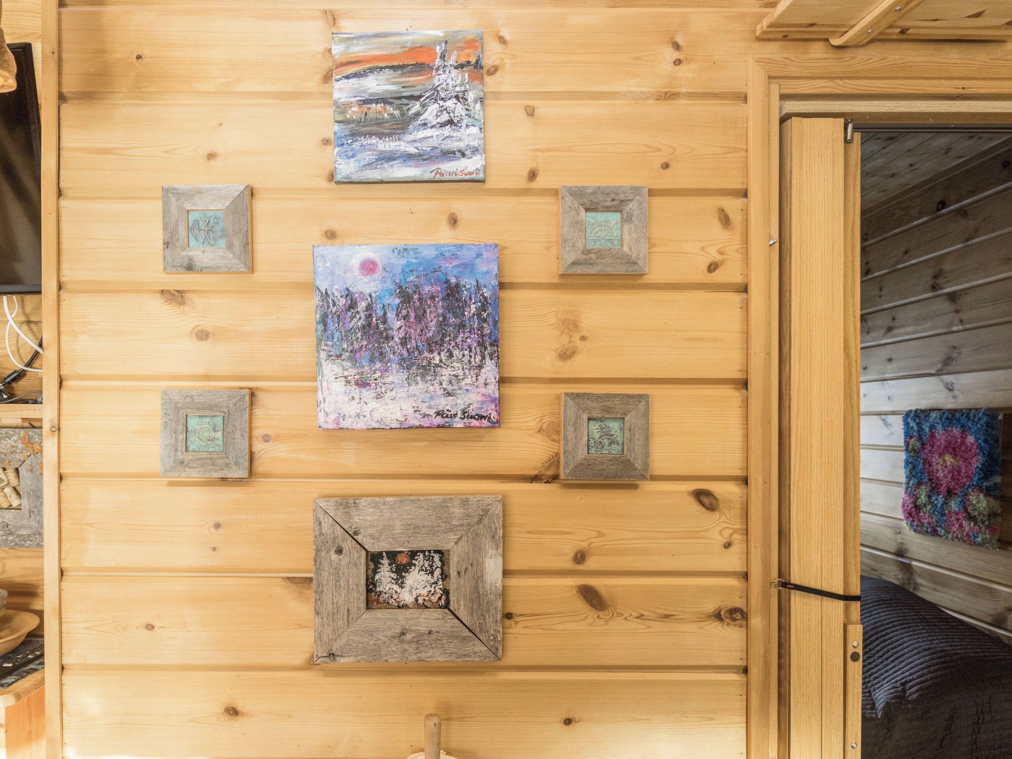Eine Holzwand mit gerahmten Kunstwerken und einer Tür.