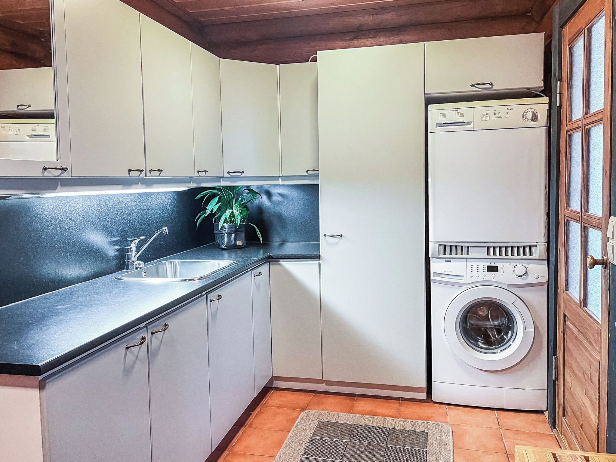 Una cocina compacta con lavadora integrada, un lavamanos y armarios.