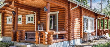 A log cabin with a porch, a door, and a window.