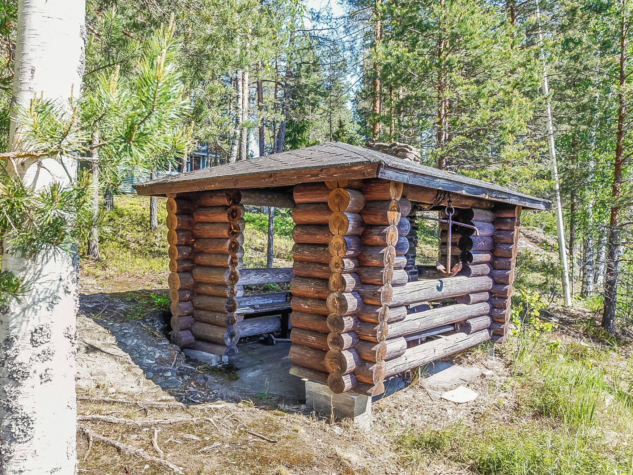 Una cabaña rústica de madera con techo inclinado, rodeada de un bosque.