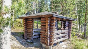 Una cabaña rústica de madera con techo inclinado, rodeada de un bosque.