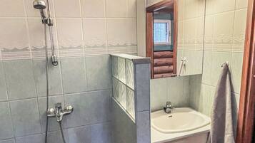 Un baño con ducha, lavabo y espejo.