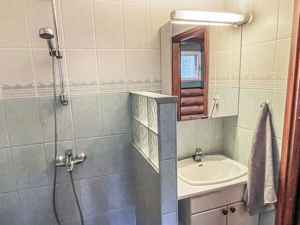 A bathroom with a shower, sink, and mirror.