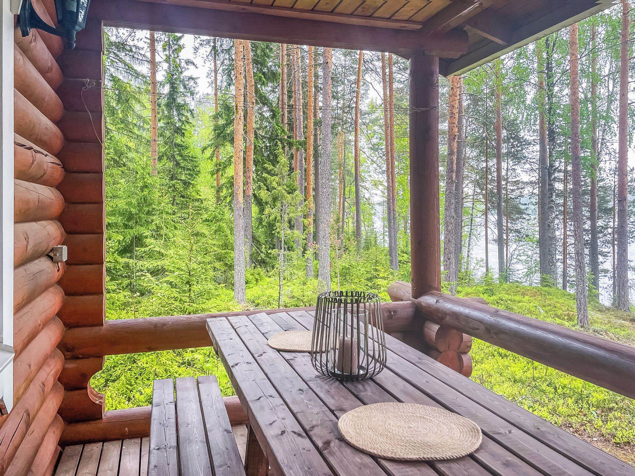 A wooden deck with a table and benches, overlooking a forest.