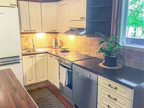 Une cuisine avec des meubles blancs, un lave-vaisselle en acier inoxydable et une cuisinière.