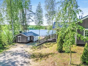 A lakeside cabin with a dock extending into the water, surrounded by trees.
