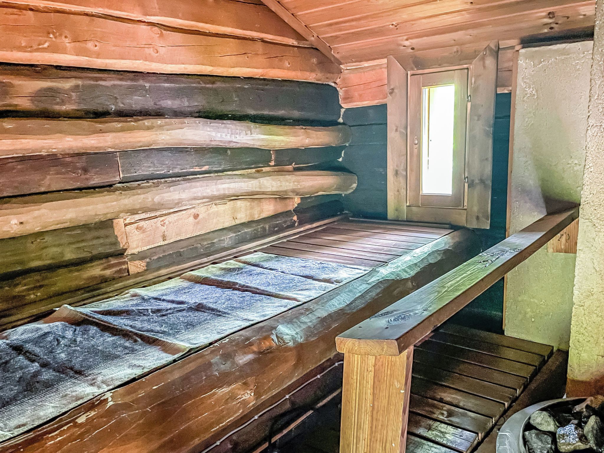 A log cabin interior with a wooden bench and a window.