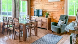 L’intérieur d’un chalet en bois comprend une table à manger, des chaises, un téléviseur et un coin salon confortable.