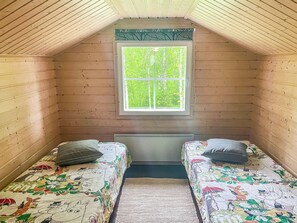A small, cozy room with two single beds, a window with a view of greenery, and a radiator under the window.