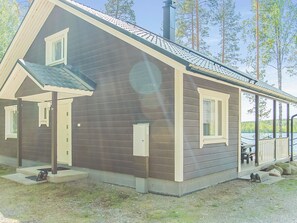 A two-story house with a covered porch, a chimney, and a view of a lake. - Saimaanhelmi by Interhome (Heinävesi)