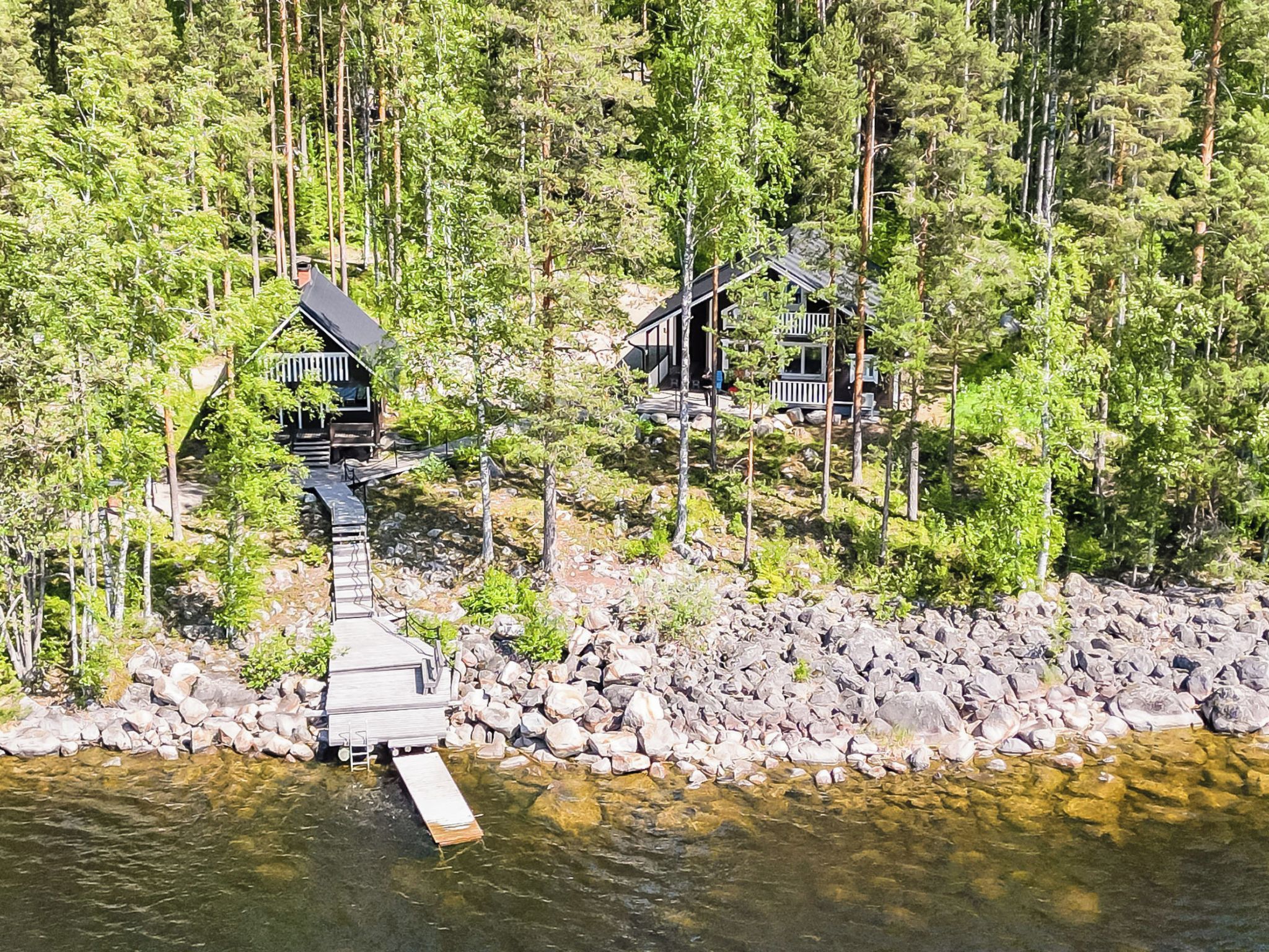 Puinen laituri johtaa pieneen mökkiin, jonka ympärillä on tiheä metsä.