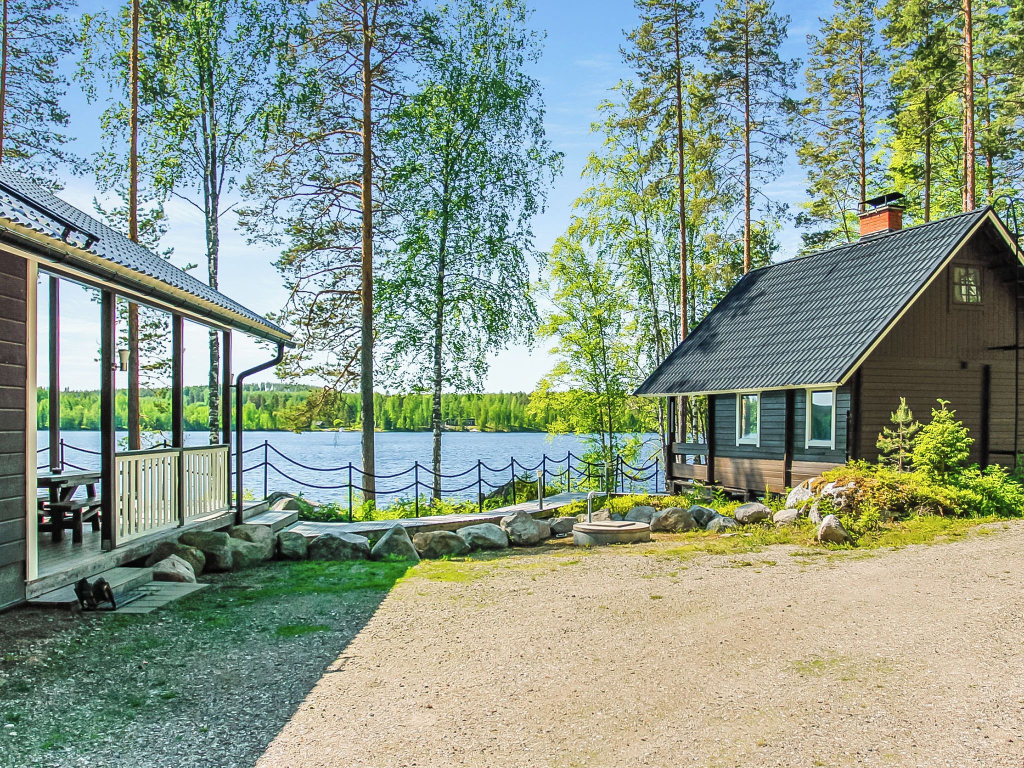 A cabin with a deck overlooking a lake, surrounded by trees.