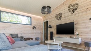 Una sala de estar moderna con un sofá seccional, una mesa de centro redonda y un televisor de pantalla plana montado en una pared de madera.