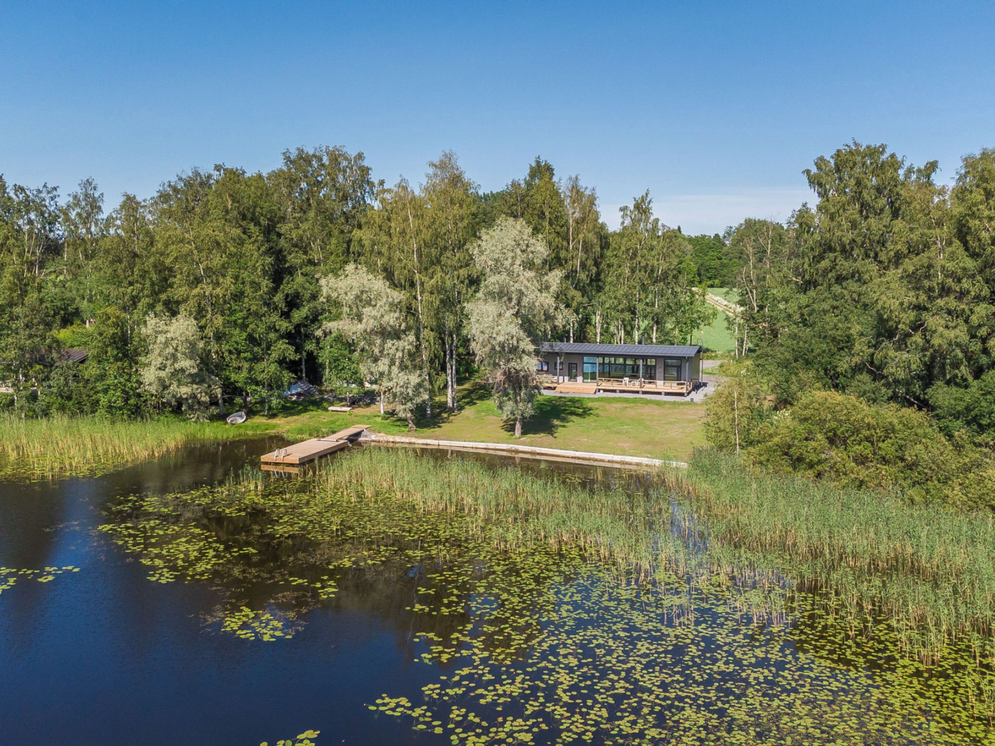 A lakeside cabin with a dock, surrounded by dense forest.