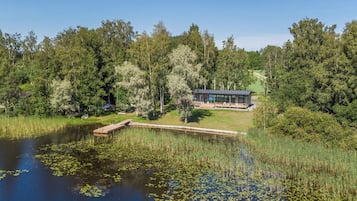 A lakeside cabin with a dock, surrounded by dense forest.
