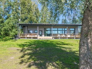 A modern building with a flat roof, large windows, and a covered outdoor seating area.