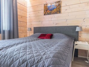 A bedroom with a bed, a headboard, a nightstand, a lamp, and a painting on the wall.