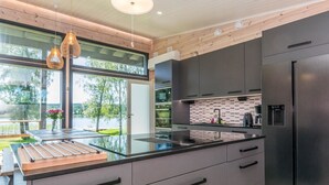 Una cocina moderna con una isla grande, muebles oscuros y vistas a un lago.