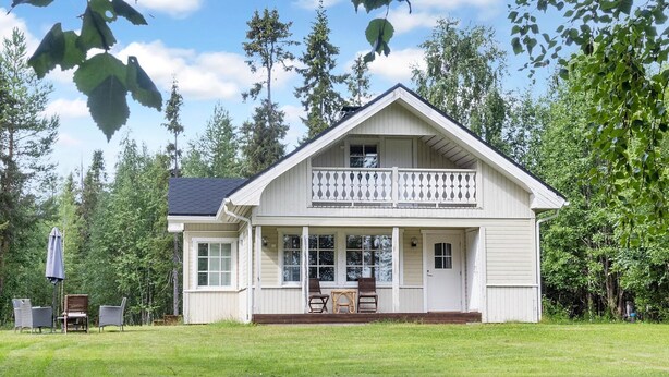 Une maison à deux étages avec un balcon, un porche et une pelouse.