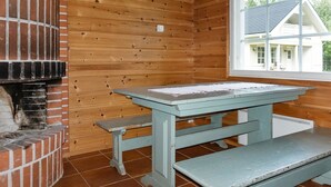 Une pièce rustique en bois, avec une cheminée en briques et une fenêtre donnant sur une maison.