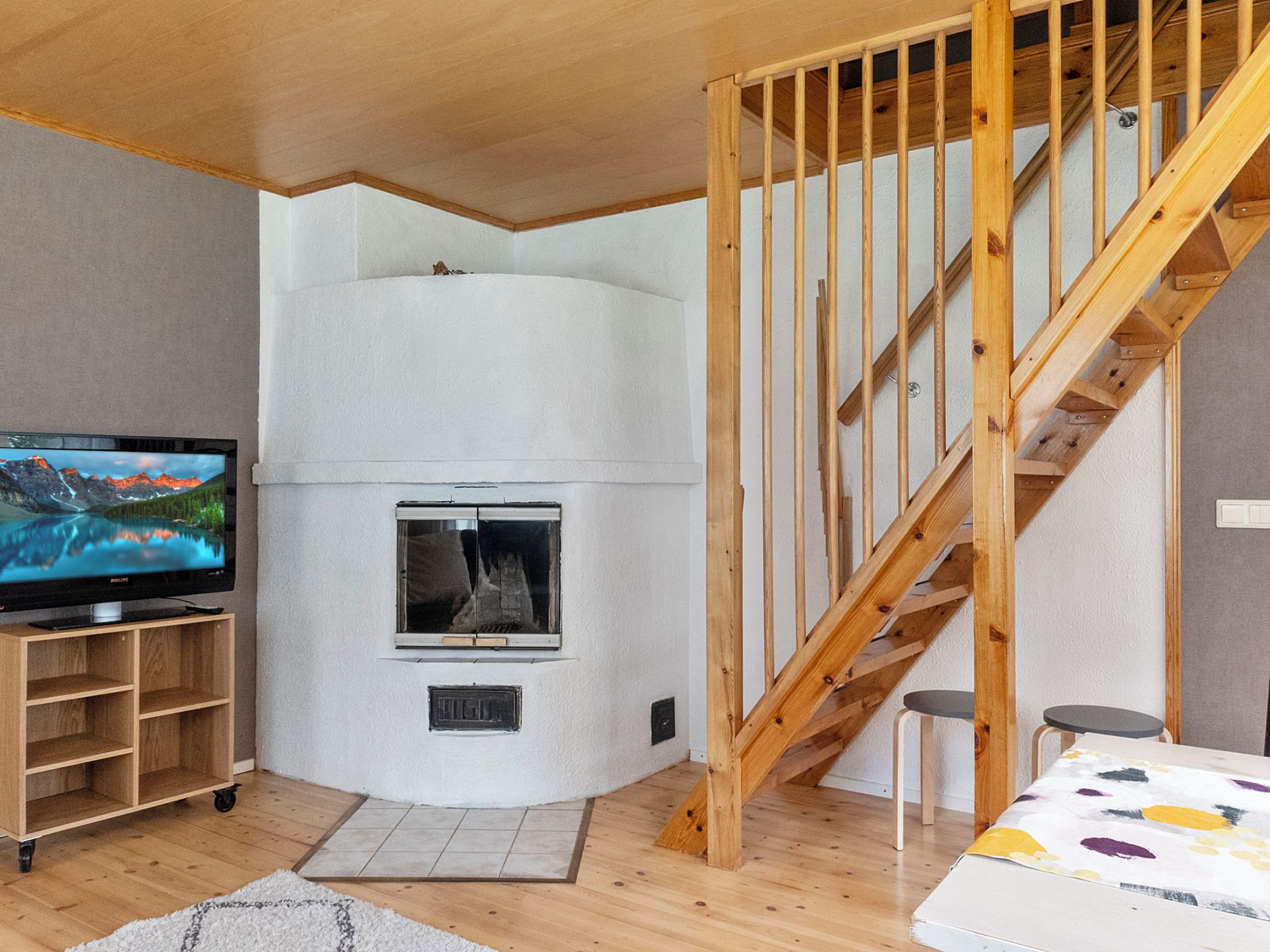 A living room with a television, a fireplace, a wooden staircase, and a sofa.