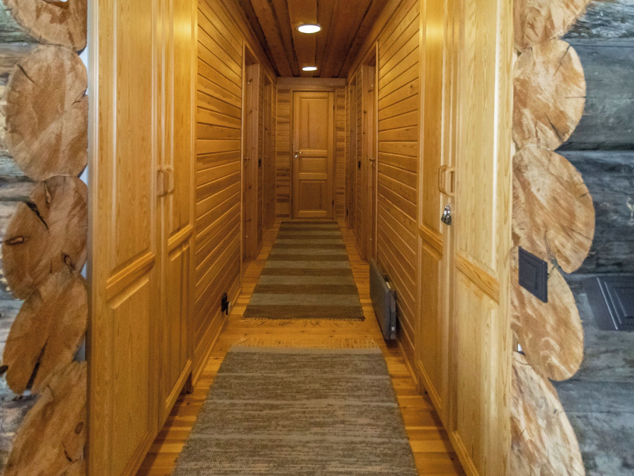 Un couloir en bois, doté d’un sol recouvert de moquette et de portes de part et d’autre.
