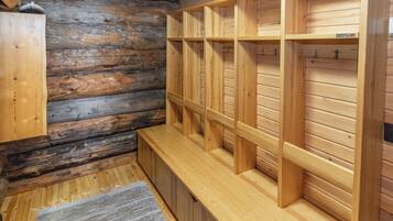 Eine Holzsauna mit Bänken und Regalen, eine Holzbank im Vordergrund und eine Steinwand im Hintergrund.