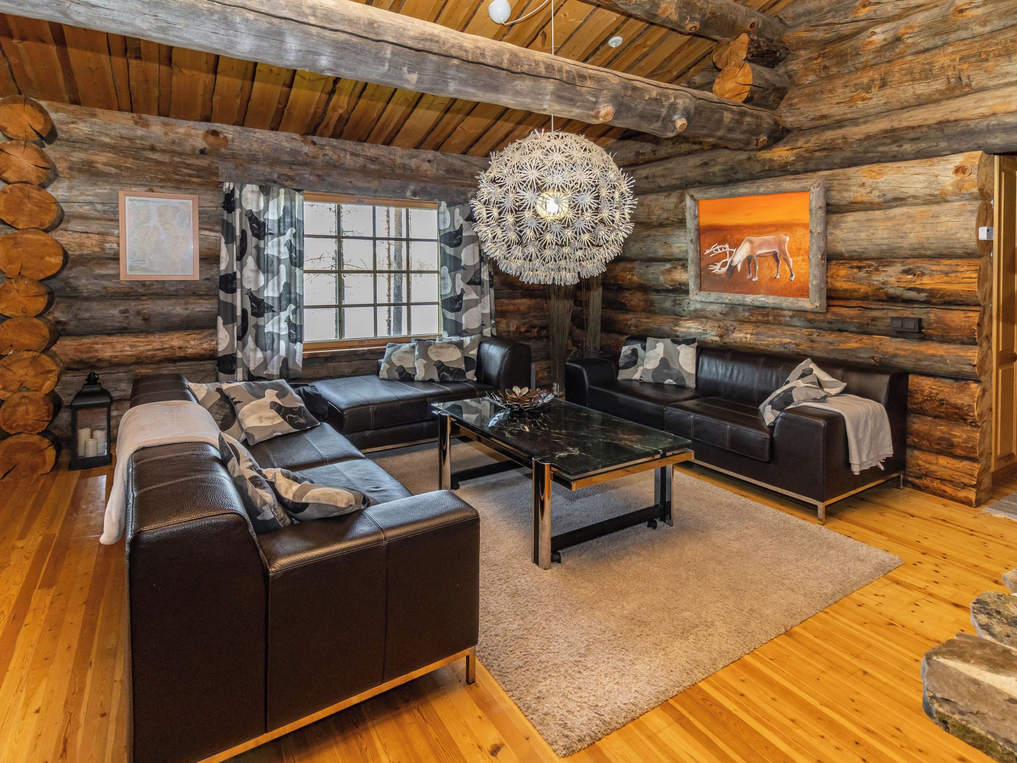A log cabin interior with a sectional sofa, a coffee table, and a large decorative light fixture.
