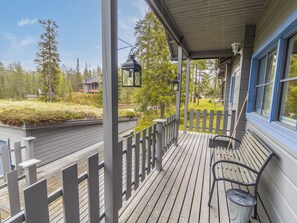 A wooden deck with a railing, a bench, and a trash can.