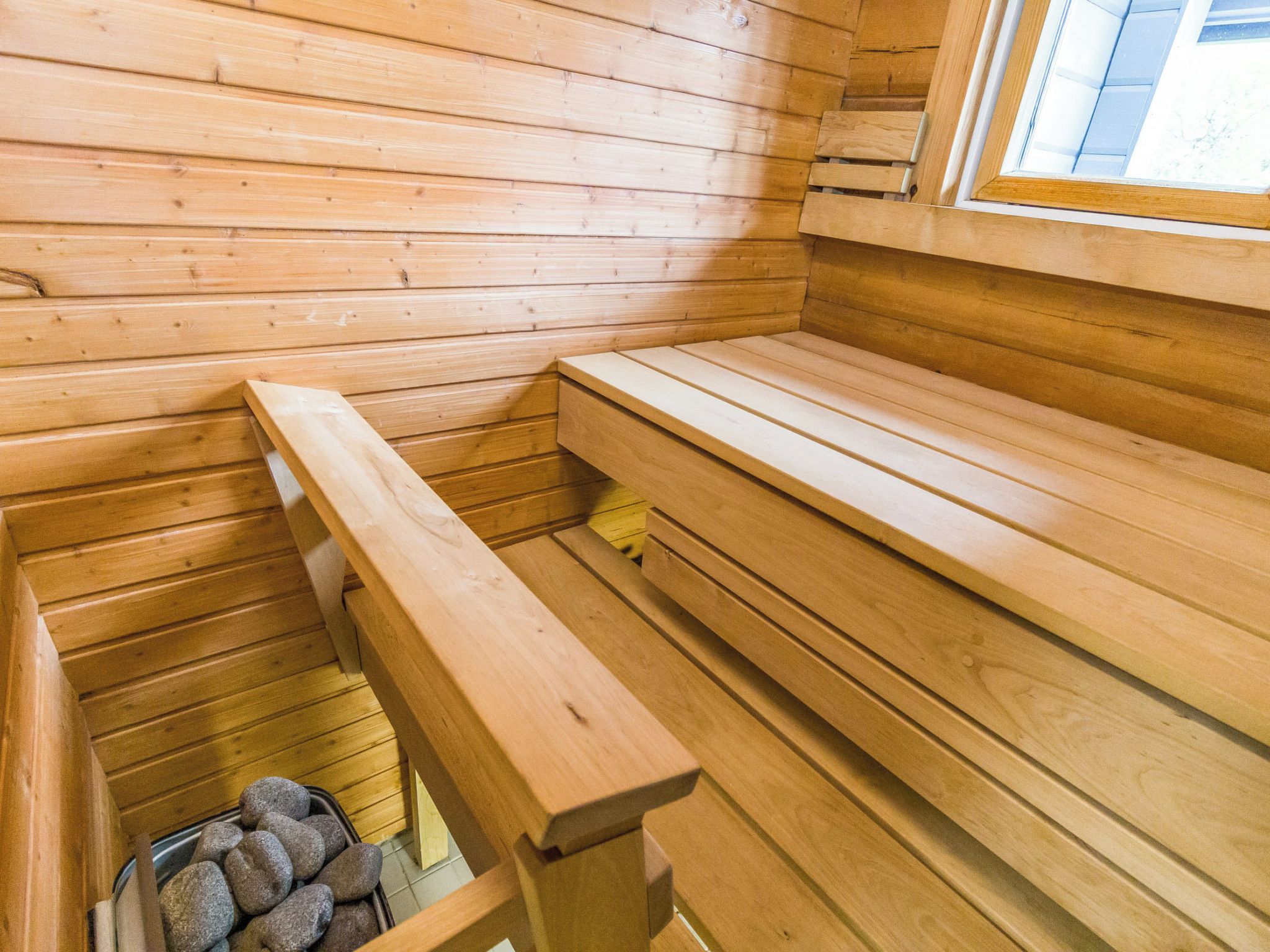 Un sauna en bois, doté de bancs et d’un bassin rempli de pierres.