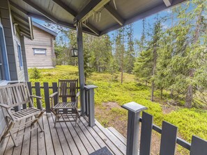 A wooden deck with a bench and a table, overlooking a forested area.