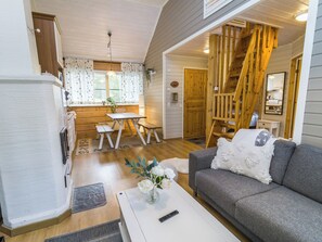 A cozy interior with a wooden staircase, a dining area, and a living room with a sofa.