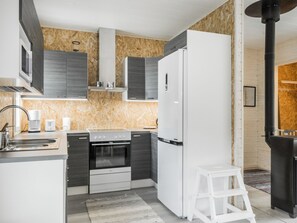 Eine moderne Küche mit eingebautem Ofen, einem Kühlschrank und einer Mikrowelle.