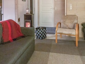 Ein Wohnzimmer mit einer Couch, einem Sessel, einem karierten Korb und einem Kamin.