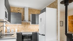 Una cocina moderna con armarios oscuros, un refrigerador blanco y un horno empotrado.